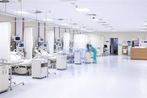 Intensive care room in a hospital, showing patients in beds and a nurse. 
